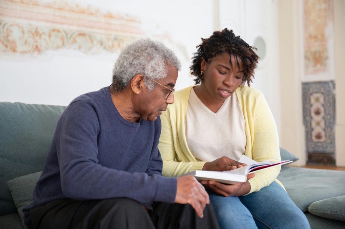 Older man reading with his carer, sharing a moment of human connection
